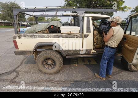 Susanville, Usa. August 2021. Der Evakuierte Rick Dewberry aus Westwood, einer kleinen Gemeinde östlich von Lake Amador Shows, organisiert seine Besitztümer auf dem Parkplatz des Lassen County Run Evakuierungszentrums in der Lassen High School in Susanville, Kalifornien während des Dixie-Feuers am 7. August 2021. Foto von Peter DaSilva/UPI Credit: UPI/Alamy Live News Stockfoto