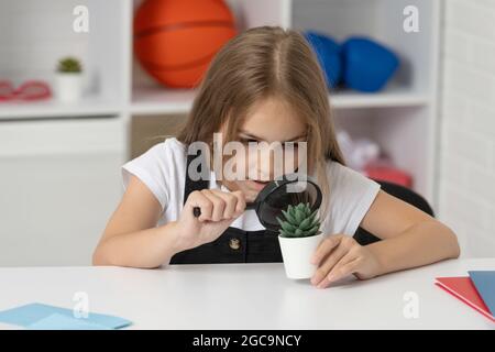 Wissenschaft und Kindheit. Jugendliches Mädchen, das die Pflanze durch Lupe betrachtet. Zurück zur Schule. Stockfoto