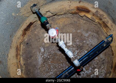 Wasserzähler in einem unterirdischen Brunnen. Pipeline für ein Landhaus. Stockfoto