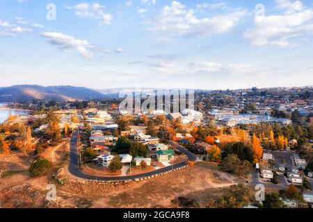 Straßen der Stadt Jindabyne am Jindabyne-See mit Snowy River und Hydrodamm in den australischen Snowy Mountains - Luftaufnahme. Stockfoto