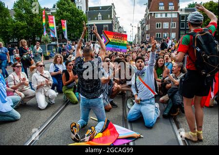 Während der Demonstration werden Demonstranten auf dem Boden sitzen und Slogans gegen Homophobie rufen sehen.die jährliche Gleichberechtigung-Demonstration für die globale Regenbogengemeinschaft fand in Amsterdam statt. Aufgrund der COVID-19-Maßnahmen begann die Demonstration nicht wie jedes Jahr am Homo-Denkmal, sondern im Martin-Luther-King-Park, wo mehr Platz für Tausende von Teilnehmern war. Der marsch ging aus dem Park, überquerte das Stadtzentrum und endete am Amsterdamer Hauptbahnhof. (Foto von Ana Fernandez/SOPA Images/Sipa USA) Stockfoto
