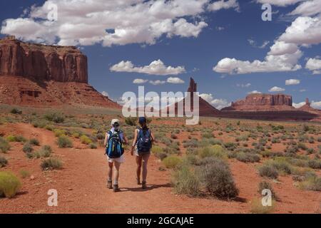 Zwei Personen wandern auf dem Wildcat Trail im Monument Valley Navajo Tribal Park, USA. Ein heißer augusttag mit blauem Himmel und Sandsteinfelsen, Buttes und Pinna Stockfoto