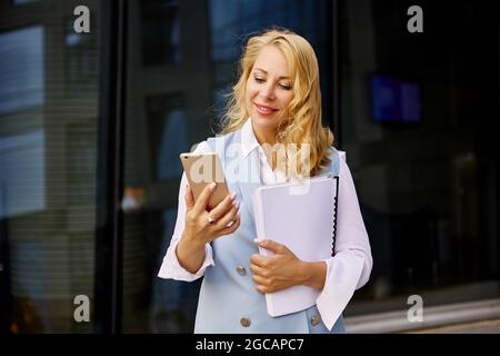 Frau im Geschäftsanzug macht Videoanruf draußen. Stockfoto