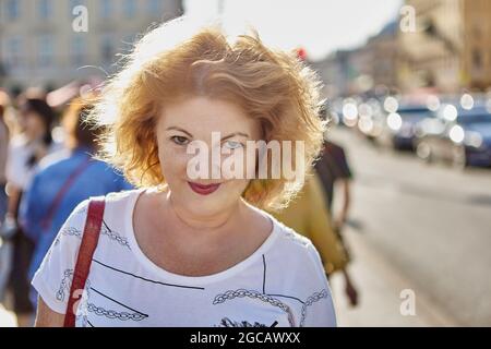 Fröhliche ältere Frau geht auf der Stadtstraße. Stockfoto