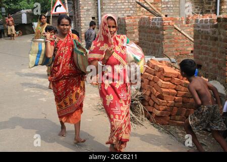 Die Menschen, die von der Überschwemmung betroffen waren, sammeln das von der Regierung des Bundesstaates bereitgestellte Material für die Überschwemmung, das am 07. August 2021 im Distrikt Howrah im indischen Bundesstaat Westbengalen nach schweren Monsunregen bereitgestellt wurde.Mehr als 4 lakh Hektar Ackerland in diesen sieben Distrikten sind jetzt unter Wasser. Starke Regenfälle und die anschließende Ableitung von Wasser aus Dämmen in den letzten Tagen haben große Teile der Distrikte Purba und Paschim Bardhaman, Paschim Medinipur, Hooghly, Howrah, South 24 Parganas und Birbhum überschwemmt. Am Donnerstag wurden 24,000 Cusec Wasser aus dem Maithon-Staudamm der Damodar Valley Corporation und freigesetzt Stockfoto
