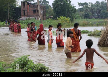 Indische Bewohner waten am 07. August 2021 auf einer überfluteten Straße nach heftigen Monsunregen im Bezirk Howrah im indischen Bundesstaat Westbengalen.Mehr als 4 lakh Hektar Ackerland in diesen sieben Bezirken sind jetzt unter Wasser. Starke Regenfälle und die anschließende Ableitung von Wasser aus Dämmen in den letzten Tagen haben große Teile der Distrikte Purba und Paschim Bardhaman, Paschim Medinipur, Hooghly, Howrah, South 24 Parganas und Birbhum überschwemmt. Am Donnerstag wurden 24,000 Cusec Wasser aus dem Maithon-Staudamm der Damodar Valley Corporation freigesetzt und es liegt im normalen Bereich, teilte ein DVC-Beamter mit. Stockfoto