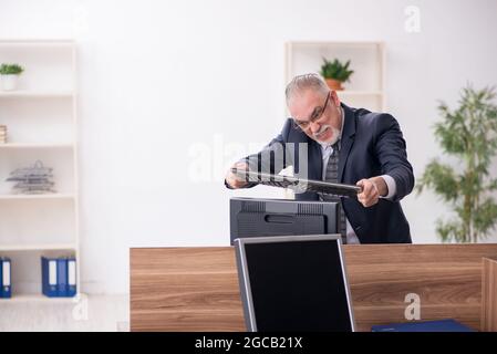 Gealterter Geschäftsmann, der am Arbeitsplatz sitzt Stockfoto