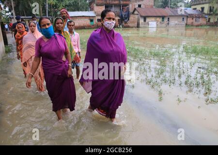 Indische Bewohner waten am 07. August 2021 auf einer überfluteten Straße nach heftigen Monsunregen im Bezirk Howrah im indischen Bundesstaat Westbengalen.Mehr als 4 lakh Hektar Ackerland in diesen sieben Bezirken sind jetzt unter Wasser. Starke Regenfälle und die anschließende Ableitung von Wasser aus Dämmen in den letzten Tagen haben große Teile der Distrikte Purba und Paschim Bardhaman, Paschim Medinipur, Hooghly, Howrah, South 24 Parganas und Birbhum überschwemmt. Am Donnerstag wurden 24,000 Cusec Wasser aus dem Maithon-Staudamm der Damodar Valley Corporation freigesetzt und es liegt im normalen Bereich, teilte ein DVC-Beamter mit. Stockfoto