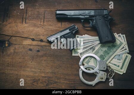 Kriminalität und Gesetz Konzept. Pistolengewehre und Geschosse 9 mm, Handschellen und American-Dollar-Banknoten auf schwarzem Hintergrund. Kriminelles Geld und Strafe, Stockfoto