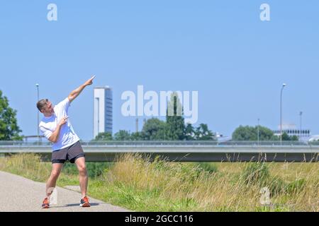 Nahaufnahme eines sportlichen Mannes mittleren Alters in Sportkleidung, der beim täglichen Joggen innehält und mit beiden Händen nach oben zeigt Stockfoto