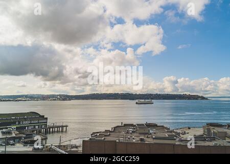 Washington Ferry fährt auf Elliot Bay mit West Seattle und Wolkenhimmel Hintergrund Stockfoto