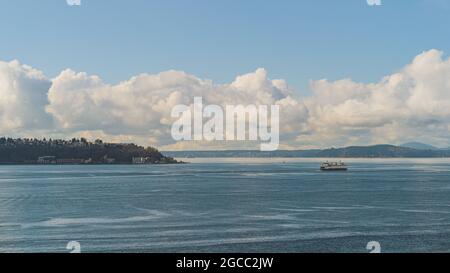 Die Washington Ferry fährt auf der Elliot Bay vorbei an West Seattle und Wolkenhimmel im Hintergrund Stockfoto