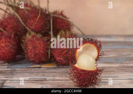 Lokale Früchte genannt Rambutan, rote Variante, die am häufigsten ist. Rambutan ist eine tropische Frucht aus der Familie der Speckbeeren. Selektiver Fokus. Verschwommener Rückstand Stockfoto