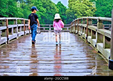 Kinder spielen im Regen auf der Brücke zur Ukimi-do Hall in Nara, Japan Stockfoto