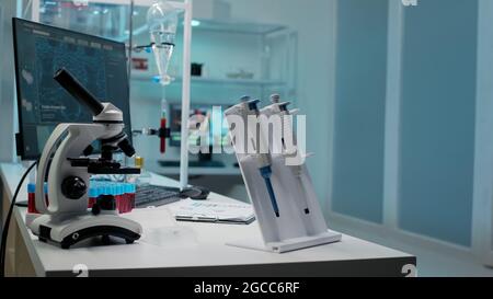 Nahaufnahme von Mikropipettenwerkzeugen und medizinischen Geräten im leeren Labor. Niemand im mikrobiologischen Raum mit Mikroskop, Staubsaugern und Blutprobe als Forschungsinstrument auf dem Schreibtisch Stockfoto