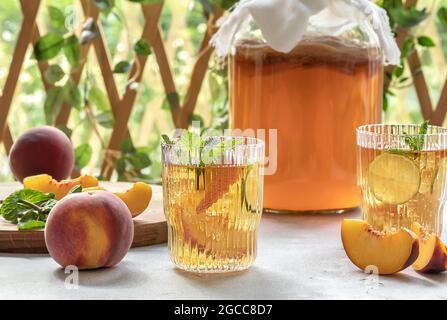 Hausgemachte Gärung. Kombucha-Tee leicht alkoholisches, leicht brausendes Getränk mit Pfirsich und Limette. Stockfoto