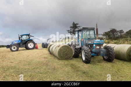 Goat's Path, Bantry, Cork, Irland. August 2021. John O'Sullivan und Thomas O'Donovan wickeln Silageballen auf der Farm ihres Nachbarn Tim Joe O'Mahony on the Goat's Path, Bantry, Co. Cork, Irland. - Bild; David Creedon / Alamy Live News Stockfoto