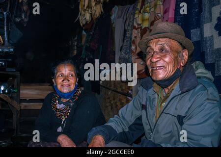 Apatani Stammespaar in ihrem Haus in der Nähe von Kamin Kochen Essen am Abend aus flachem Winkel Bild wird bei ziro arunachal pradesh indien genommen Stockfoto