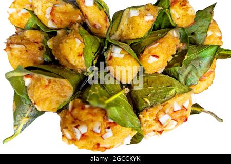 Traditioneller, gedämpfter, reifer palmyra-Palmenfruchtkuchen, eingewickelt mit Jackfruitblättern und mit Kokosnussstücken bestreut. Gedämpfter palmyra Palmkuchen in Isolate Stockfoto