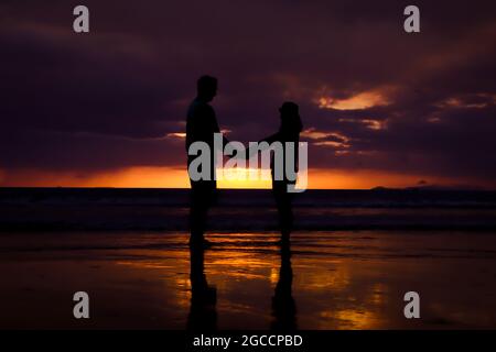 Silhouette des Paares halten sich die Hand und Happy Young Paar lieben am Strand bei Sonnenuntergang Stockfoto