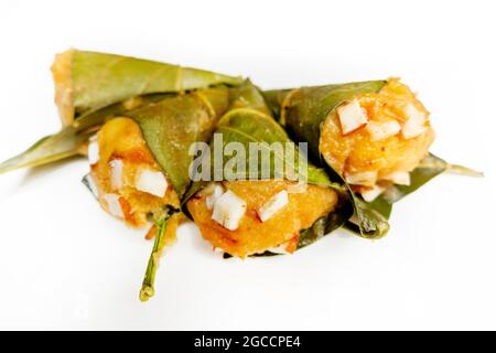 Traditioneller, gedämpfter, reifer palmyra-Palmenfruchtkuchen, eingewickelt mit Jackfruitblättern und mit Kokosnussstücken bestreut. Gedämpfter palmyra Palmkuchen in Isolate Stockfoto