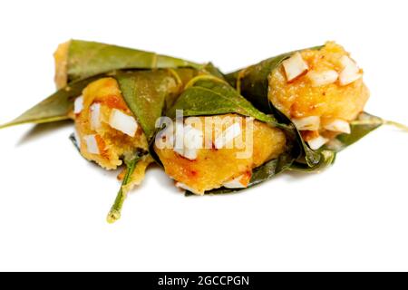 Traditioneller, gedämpfter, reifer palmyra-Palmenfruchtkuchen, eingewickelt mit Jackfruitblättern und mit Kokosnussstücken bestreut. Gedämpfter palmyra Palmkuchen in Isolate Stockfoto