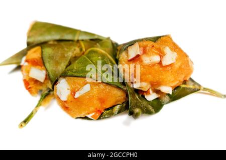 Traditioneller, gedämpfter, reifer palmyra-Palmenfruchtkuchen, eingewickelt mit Jackfruitblättern und mit Kokosnussstücken bestreut. Gedämpfter palmyra Palmkuchen in Isolate Stockfoto