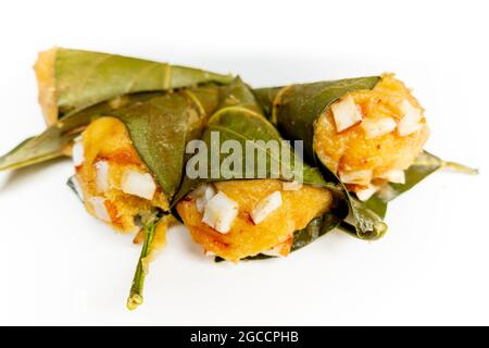 Traditioneller, gedämpfter, reifer palmyra-Palmenfruchtkuchen, eingewickelt mit Jackfruitblättern und mit Kokosnussstücken bestreut. Gedämpfter palmyra Palmkuchen in Isolate Stockfoto