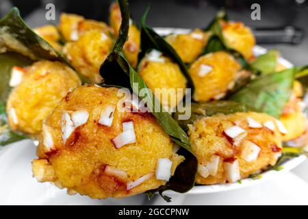 Traditioneller, gedämpfter, reifer palmyra-Palmenfruchtkuchen, eingewickelt mit Jackfruitblättern und mit Kokosnussstücken bestreut. Gedämpfter palmyra Palmkuchen in Nahaufnahme Stockfoto