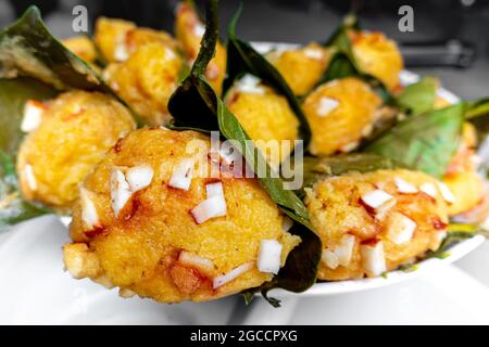 Traditioneller, gedämpfter, reifer palmyra-Palmenfruchtkuchen, eingewickelt mit Jackfruitblättern und mit Kokosnussstücken bestreut. Gedämpfter palmyra Palmkuchen in Nahaufnahme Stockfoto