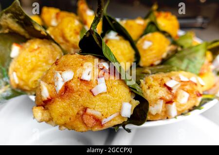 Traditioneller, gedämpfter, reifer palmyra-Palmenfruchtkuchen, eingewickelt mit Jackfruitblättern und mit Kokosnussstücken bestreut. Gedämpfter palmyra Palmkuchen in Nahaufnahme Stockfoto