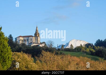 Die Kirche San Esteban de Galdames mit dem schneebedeckten Pico de la Cruz im Hintergrund Stockfoto