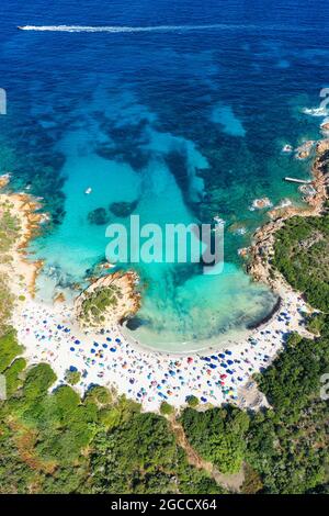 Blick von oben, atemberaubender Panoramablick auf einen weißen Sandstrand voller Sonnenschirme und Menschen, die in einem türkisfarbenen Wasser schwimmen. Stockfoto