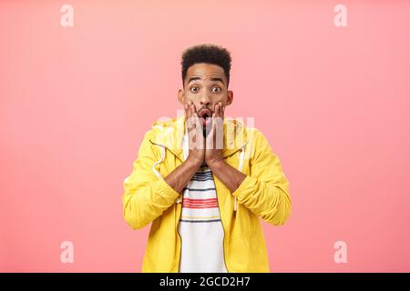 Erfreut überrascht nette afroamerikanische Kerl in stilvollem Outfit mit Bart und lockigen Haarschnitt Falten geöffneten Mund in wow Sound keuchend Hände halten Stockfoto