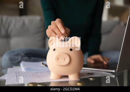 Nahaufnahme Frau, die Münze in Sparschwein legt, Investitionskonzept Stockfoto
