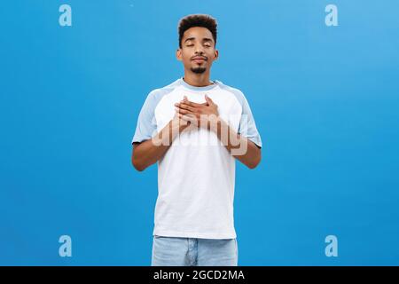 Kerl finden Frieden in Poesie atmen frische Luft Schließen der Augen mit friedlichen entspannten Ausdruck lächelnd Handflächen auf Herz entlastet von Stress Stockfoto