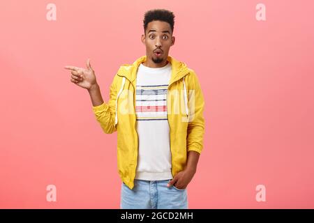 Studio-Aufnahme von überrascht beeindruckt stilvollen afroamerikanischen männlichen Studenten in trendigen gelben Jacke Falten Lippen in Wow-Sound Anheben Augenbrauen aus Stockfoto