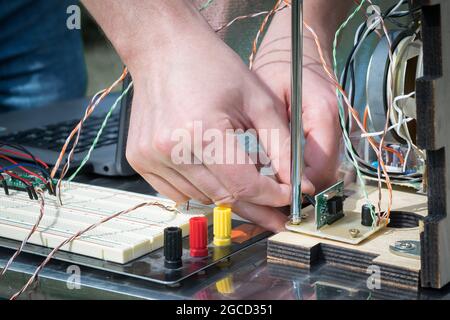 Die Hände verbinden elektronische Kontakte des selbstgebauten Radios. Hobby Retro-Dinge zu machen. Stockfoto