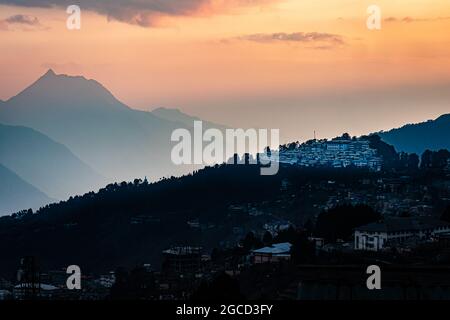 tawang alte buddhistische Kloster Ansicht mit orangefarbenem Himmel und Bergschatten von der Spitze des Hügels am Abend Bild wird an der riesigen buddha-Statue tawang aruna aufgenommen Stockfoto