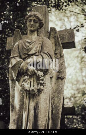 Viktorianische Steinengelstatue mit Kreuz auf dem historischen Friedhof Stockfoto