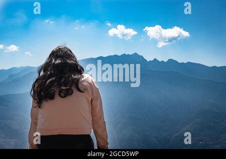 Junges Mädchen, das morgens aus flachem Winkel das neblige Bergtal beobachtet Stockfoto