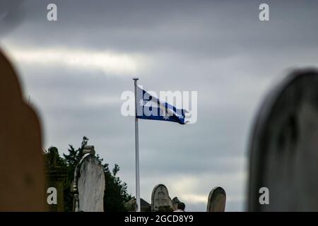 Die Eureka-Flagge fliegt an einem trüben, bewölkten Tag auf dem alten Friedhof von Ballarat im Wind Stockfoto