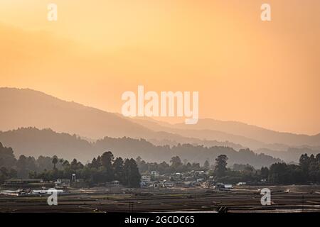 Bergschichten mit Dorf an den Ausläufern und orangefarbenem Morgenhimmel in der Morgendämmerung Bild wird in ziro arunachal pradesh indien aufgenommen. Stockfoto