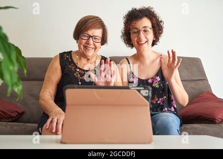 Eine ältere Frau mit ihrer Tochter führt per Tablet einen Videoanruf durch Stockfoto