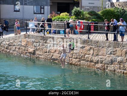 An einem heißen Sommertag tauchte und schwamm man in Penzance Harbour, Cornwall, Großbritannien Stockfoto