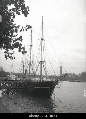 1950er Jahre, historische Ansicht des berühmten Barque-Rigged-Segelschiffs "RRS Discovery" auf der Themse, London, England, Großbritannien, das letzte hölzerne Dreimast-Schiff, das in Großbritannien gebaut wurde. Sie war ein Segelschiff mit einem zusätzlichen Dampfantrieb und wurde in Dundee, Schottland, gebaut. Ihre erste Reise, die als Discovery Expedition (1901-1904) bekannt ist, wurde speziell für die Antarktisforschung gebaut und führte die britischen Forscher Robert Falcon Scott und Ernest Shackletone in die Region. Nachdem sie von 1929 bis 1931 in der australischen Antarktis war, wurde sie als statisches Trainingsschiff und Besucherattraktion auf der Themse festgemacht. Stockfoto