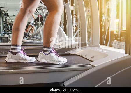 Nahaufnahme Schuhe Frau läuft auf Laufband. Frau mit muskulösen Beinen im Fitnessstudio Stockfoto