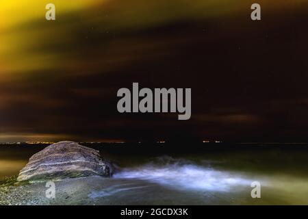 Mystische Nachtlandschaft am Meer mit Sternenhimmel. Meereswellen verschwimmen in Bewegung Stockfoto