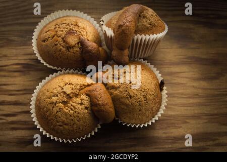 Flache Verlegung von vier Muffins, die in einem überhitzten Ofen zubereitet wurden, Beispiel für einen Fehler bei der Gartemperatur von Desserts und Süßigkeiten Stockfoto