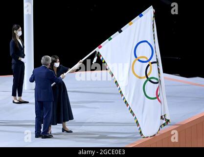 Tokio, Japan. August 2021. Olympia: Abschlussfeier im Olympiastadion. Olympische Spiele: Abschlussfeier im Olympiastadion. Die Bürgermeisterin von Paris, dem nächsten Austragungsort der Olympischen Spiele, Anne Hidalgo, erhält die olympische Flagge vom Präsidenten des Internationalen Olympischen Komitees, Thomas Bach. Quelle: Marijan Murat/dpa/Alamy Live News Stockfoto